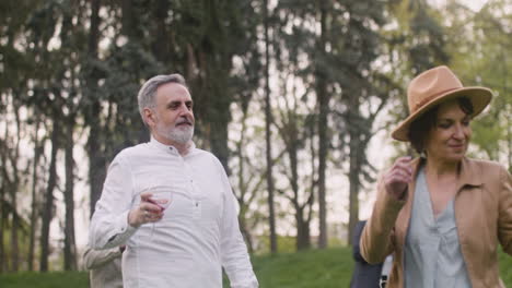 Middle-Aged-Man-And-Woman-Dancing-While-Holding-Wine-Glasses-In-The-Park