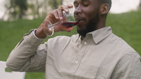 Man-Taking-A-Glass-Of-Wine-From-A-Table-And-Drinking-It-During-A-Garden-Party-In-The-Park