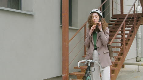 Pretty-Curly-Woman-In-Formal-Clothes-Wearing-A-Bicycle-Helmet-In-The-City