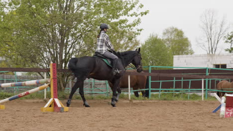 Young-Female-Jockey-Riding-Black-Horse-Outside