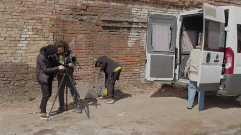 Two-Production-Co-Workers-Setting-Up-A-Camera-In-The-Street-And-Other-Two-Workers-Taking-Material-For-A-Recording-From-A-Van