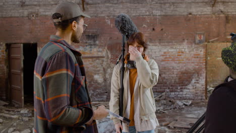 Two-Coworkers-Holding-Material-For-A-Recording-While-Talking-And-Laughing-In-A-Ruined-Building