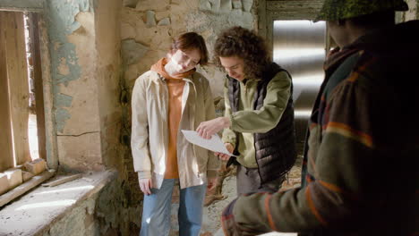 A-Production-Worker-Helping-His-Female-Coworker-Read-A-Script-In-A-Ruined-Building