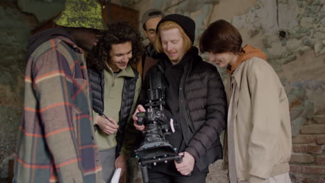 Production-Team-And-Cameraman-Laughing-While-Reviewing-A-Scene-In-A-Camera-In-A-Ruined-Building