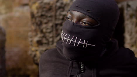 Close-Up-View-Of-Man-Wearing-Black-Balaclava-And-Holding-An-Ax-In-A-Ruined-Building