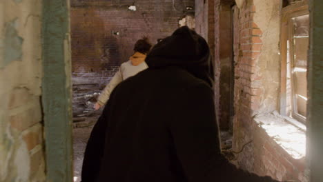 Rear-View-Of-A-Man-In-Black-Balaclava-And-Holding-An-Ax-Persecuting-A-Redheaded-Girl-In-A-Ruined-Building-1