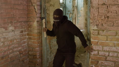 Man-In-A-Balaclava-And-Holding-An-Ax-Running-In-A-Ruined-Building