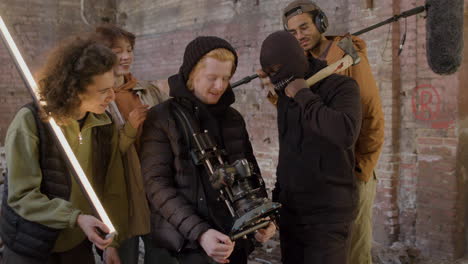 Production-Team,-Cameraman-And-Actors-Reviewing-A-Scene-Movie-In-A-Camera-And-Laughing-In-A-Ruined-Building