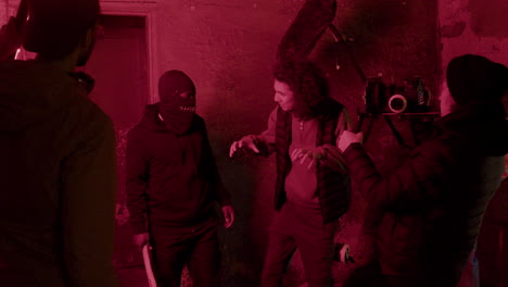 Cameraman-And-Production-Worker-Giving-Instructions-To-An-Man-In-Black-Balaclava-For-A-Movie-Scene-In-A-Ruined-Building