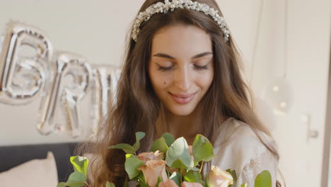 Bride-holding-bouquet-with-hair-band-with-flowers,-looking-at-camera-while-smiling