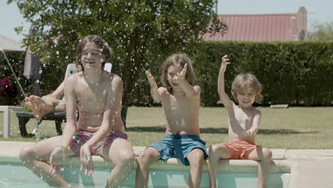 Cute-kids-sitting-on-edge-of-swimming-pool-and-splashing-water