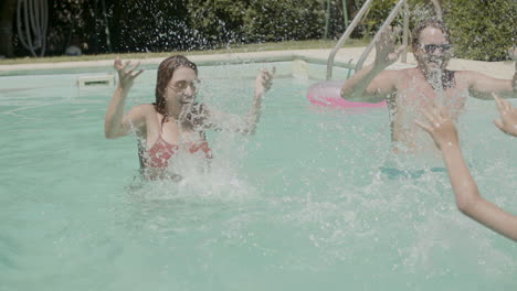 Cheerful-parents-splashing-water-in-swimming-pool-with-kids