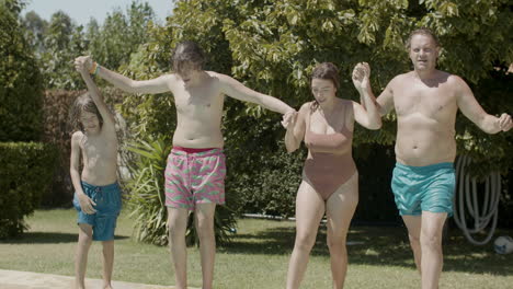 Cheerful-parents-and-kids-holding-hands-and-running-into-swimming-pools-together