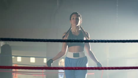 Front-view-of-a-young-Caucasian-sportswoman-with-braided-pigtails-jumping-rope-in-boxing-ring