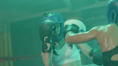 Two-female-boxers-in-helmets-and-boxing-gloves-training-in-ring