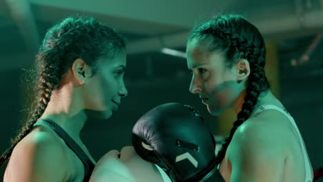 Zwei-Boxerinnen-Bereiten-Sich-Auf-Den-Kampf-Vor,-Stehen-Sich-Gegenüber-Und-Halten-Intensiven-Blickkontakt-Miteinander