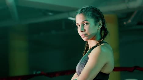 Young-female-boxer-with-braided-pigtails-posing-at-ther-camera-while-training-in-the-gym
