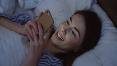 Close-up-view-of-the-charming-Caucasian-woman-with-dark-hair-lying-in-the-bed,-chatting-on-the-smartphone-late-at-night