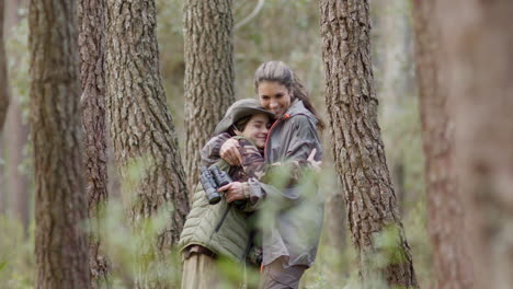 Mother-and-son-standing-in-the-forest,-looking-at-the-camera-and-hugging