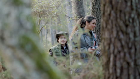 Tracking-shot-of-young-kid-and-his-mother-with-camera-walking-in-the-woods-and-exploring-wildlife