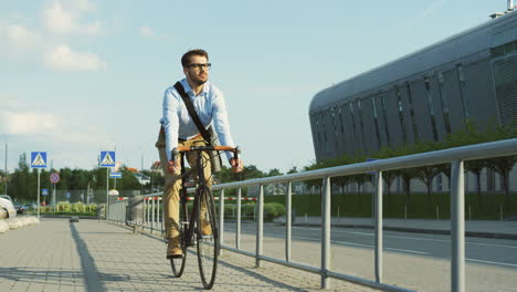 Hombre-Guapo-Usando-Auriculares,-Usando-Anteojos-Y-Estilo-Informal-Y-Montando-En-Bicicleta