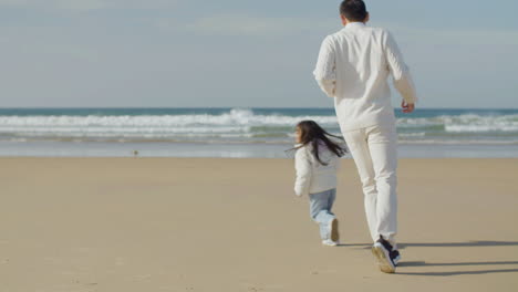 Japanese-father-and-little-daughter-running-and-playing-game-of-tag-on-the-beach