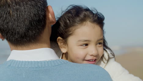 Close-up-shot-of-a-happy-cute-little-Japanese-girl-hugging-her-dad-at-the-beach
