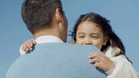 Close-up-shot-of-a-happy-cute-little-Japanese-girl-hugging-and-kissing-her-dad-at-the-beach