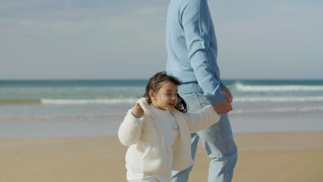 Japanese-father-and-his-cute-little-daughter-walking-along-seashore