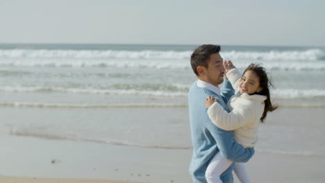 Loving-Japanese-dad-holding-his-little-daughter-in-his-arms-and-dancing-on-the-beach