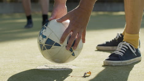 Close-up-of-an-unrecognizable-sportsman-putting-soccer-ball-on-ground-and-kicking-it
