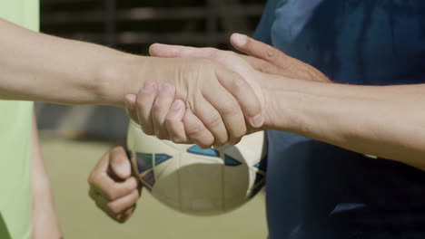 Close-up-of-two-unrecognizable-senior-football-players-shaking-hands-before-soccer-match