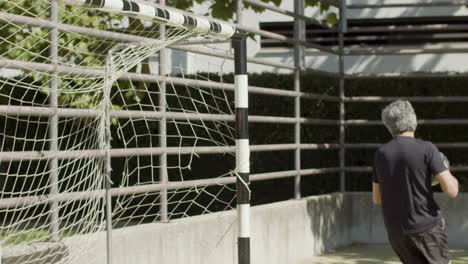 Side-view-of-a-focused-senior-goalkeeper-defending-the-soccer-goal-and-catching-the-ball