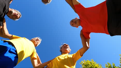View-from-below-of-senior-football-players-jumping-in-circle-and-clapping-hands-before-workout