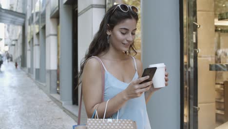 Mujer-Sonriente-Usando-Teléfono-Inteligente,-Leyendo-Chat-Y-Tomando-Café