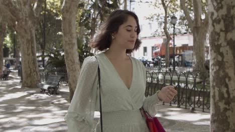 Mujer-Joven-Latina-Sosteniendo-Bolsas-En-El-Codo-Y-Caminando-Por-La-Calle