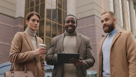 Bottom-view-of-caucasian-businesswoman-holding-coffee,-african-american-man-watching-to-a-tablet-and-caucasian-man-in-the-street-in-autumn