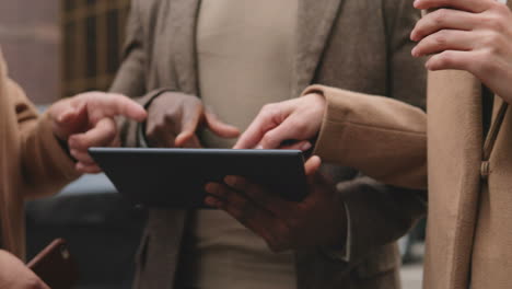 Close-up-view-of-african-american-man-hands-holding-a-tablet-and-Caucasian-male-and-female-hands-pointing-something-on-its-screen