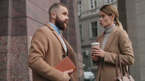 Caucasian-businessman-and-businesswoman-talking-and-drinking-coffee-in-the-street-in-autumn,-then-African-American-man-approachs-to-them