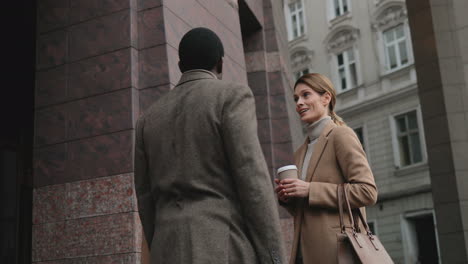 Caucasian-businessman-and-businesswoman-talking-and-drinking-coffee-in-the-street-in-autumn,-then-African-American-and-caucasian-man-approach-to-them