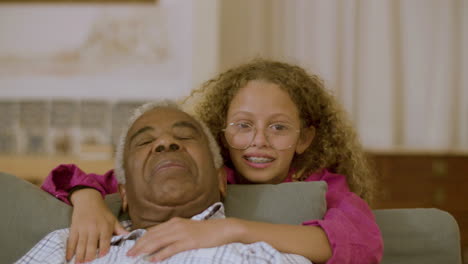 Closeup-of-loving-granddaughter-hugging-her-grandpa-and-smiling