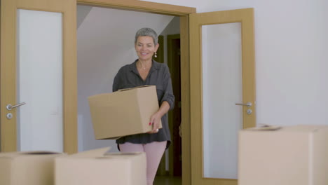 Happy-beautiful-mature-woman-entering-new-house-with-cardboard-boxes