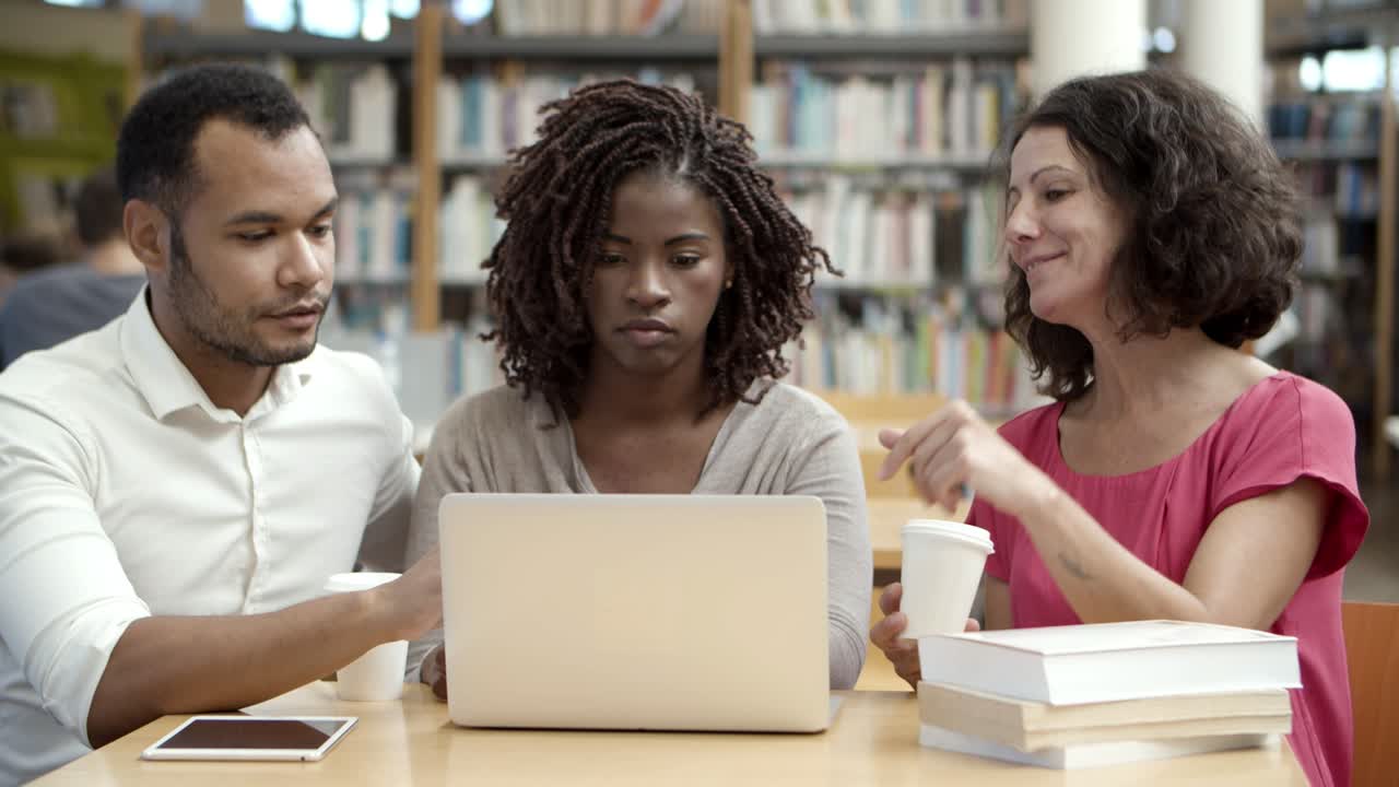 Free stock video - Thoughtful people talking while using laptop at library