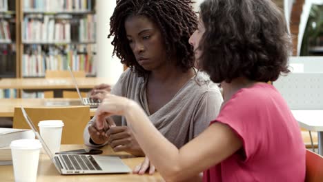 Mujeres-Enfocadas-Usando-Laptop-En-La-Biblioteca