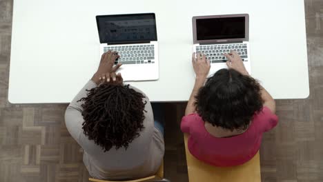 Vista-Superior-De-Las-Mujeres-Que-Trabajan-Con-Computadoras-Portátiles-Mientras-Están-Sentadas-En-La-Mesa