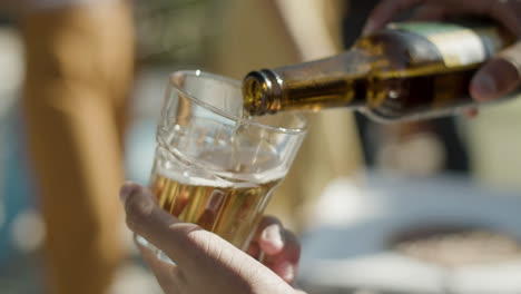 Close-up-shot-of-an-unrecognizable-man-holding-glass-in-hand-and-pouring-beer-into-it