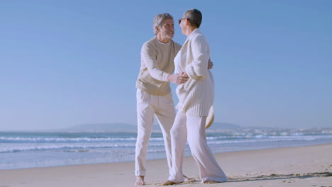 Happy-senior-Caucasian-couple-dancing-on-the-beach-on-a-sunny-day