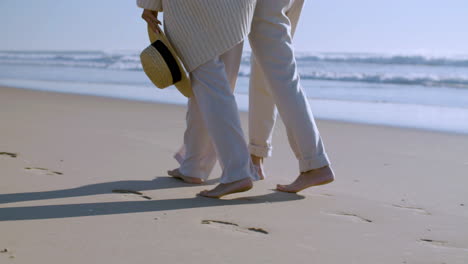Close-up-of-an-unrecognizable-couple-walking-on-the-beach