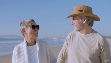 Front-view-of-a-happy-senior-Caucasian-couple-talking-and-laughing-together-while-walking-on-the-beach