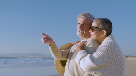 Romantic-senior-couple-hugging-while-talking-and-enjoying-the-view-on-the-beach